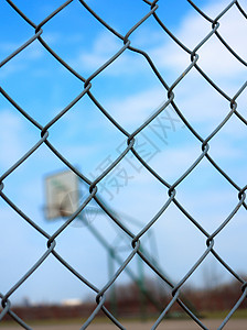 模糊篮球场背景的金属网状铁丝栅栏背景图片
