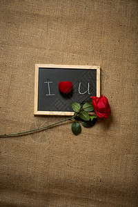 红玫瑰和结婚戒指躺在写黑板上的爱情宣言图片