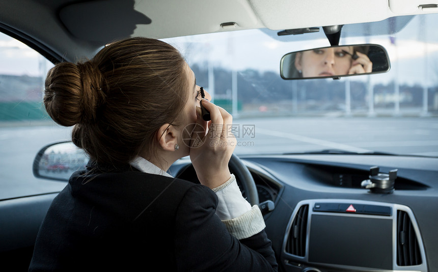 年轻女商人在汽车中使用马斯卡拉的肖像图片
