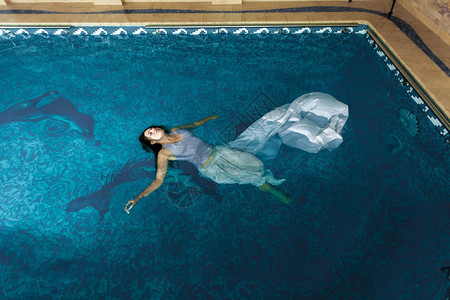 穿着长白色裙的感女人在游泳池水面图片