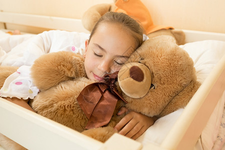睡在大泰迪熊床上的小女孩肖像图片
