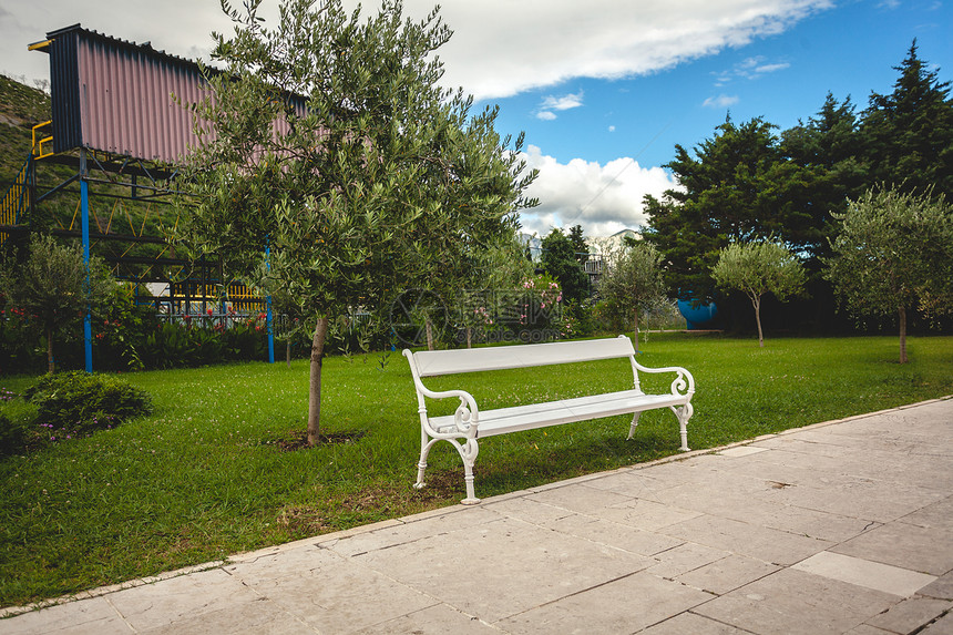公园白色长凳的美丽景有树木和草坪图片