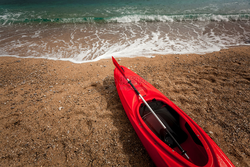 蓝色大浪海中美丽沙滩上红色皮艇的近照片图片