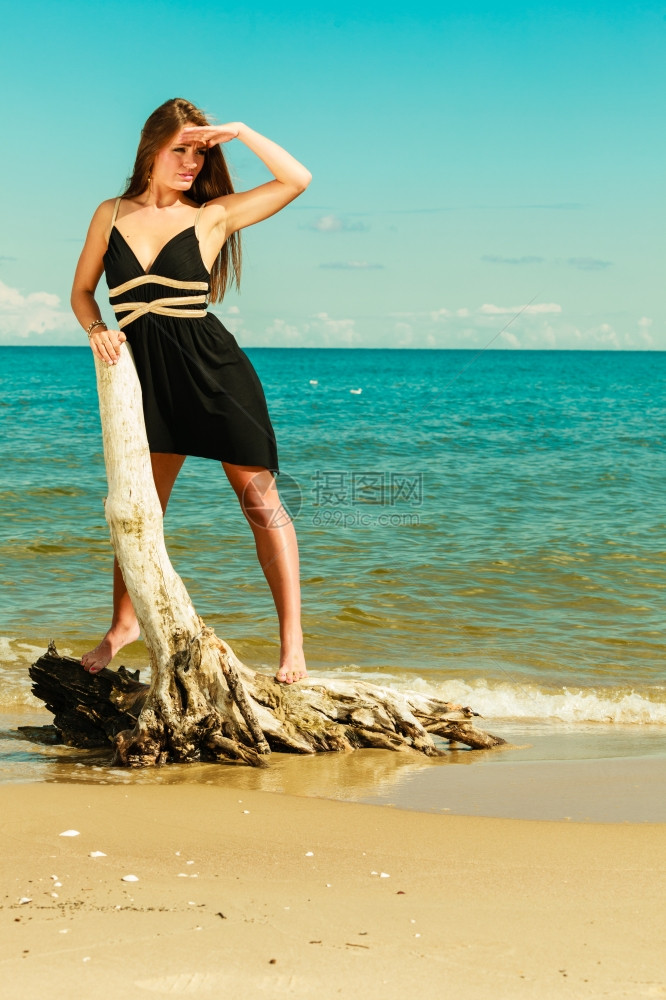 假期旅行和自由概念海滩上长头发的漂亮感美女长发穿暑期服装的年轻漂亮棕色女子在海边放松站干树根上图片