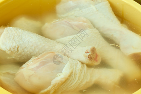 水鸡把生鸡肉腿放在水里洗干净准备食物背景