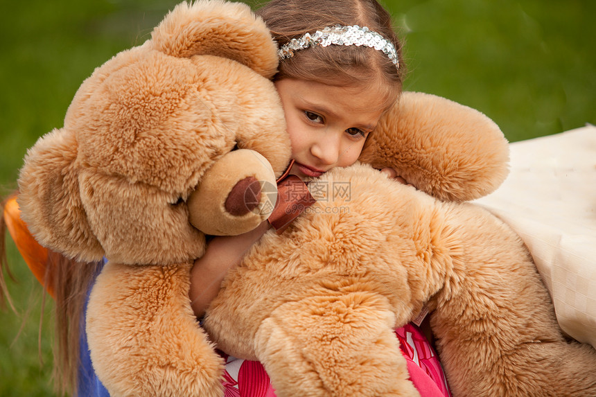 悲伤的小女孩抱泰迪熊的近照图片
