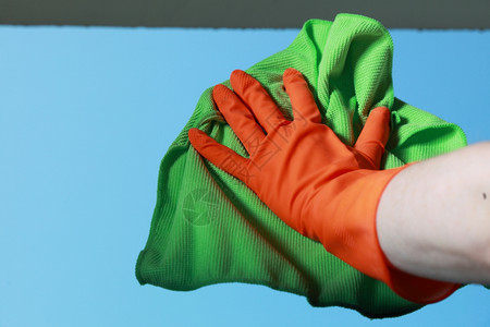 用绿色抹布橙手套清洗窗户背景图片