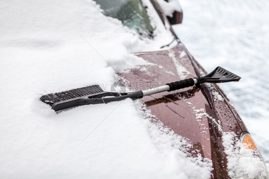 黑色刷子的近照片躺在被雪覆盖的汽车上图片