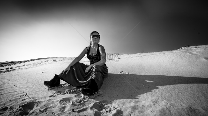 坐在沙丘上的疲劳妇女黑白照片图片