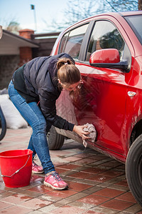 汽车加油桶年轻瘦女人用地毯洗红色汽车门背景
