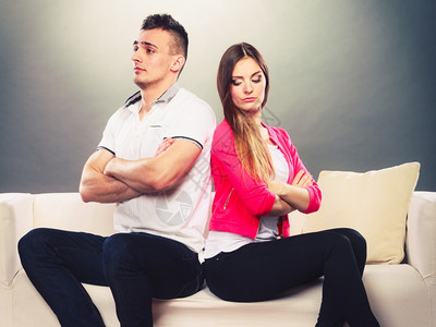 男人和女意见不一争吵后的年轻情侣坐在沙发上背对女人高清图片素材