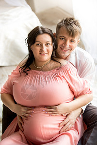 英俊男人的肖像拥抱背上胖的怀孕妻子图片