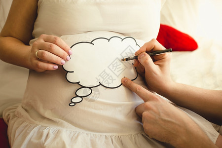 在Wife怀孕腹部的纸牌上写字男子照片剪贴画高清图片素材