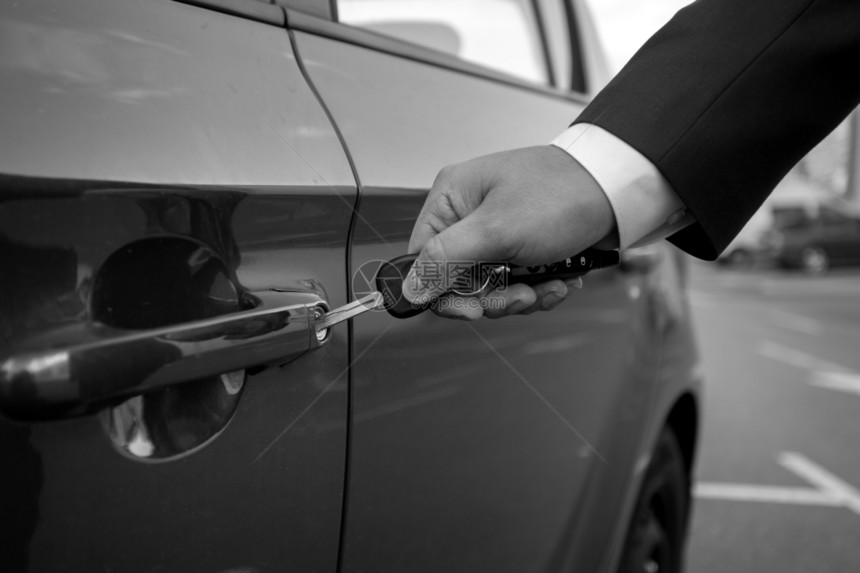 男子在汽车驾驶门插入车钥匙的特写镜头图片