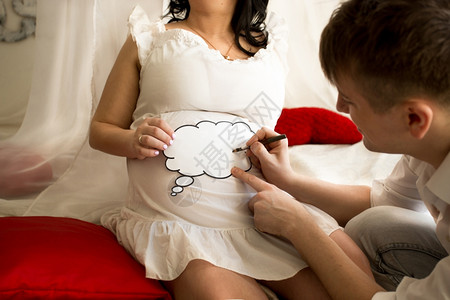 年轻男子在妻和上持有复制空间标志的年轻男子怀孕肚签名高清图片素材