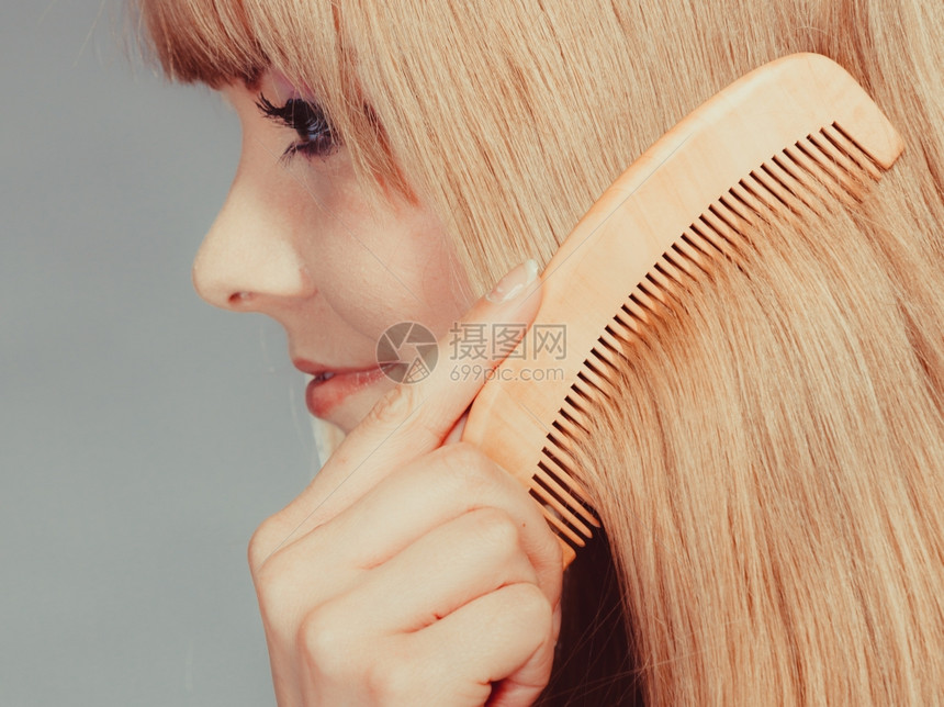 健康美容和理发概念缝合年轻金发女郎用木梳子理长发缝合图片