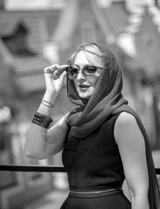 身着围巾和眼镜在街上摆姿势的优雅女子黑白近身肖像图片