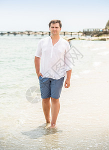穿白衬衫的帅男子在海边行走图片