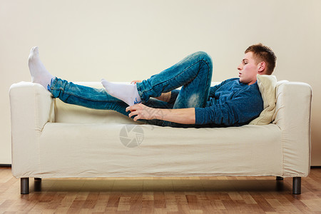 在家休闲概念英俊的年轻人在沙发上放松穿袜子图片
