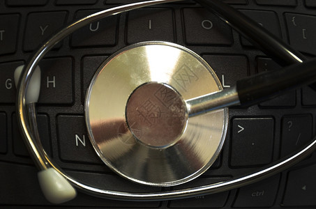 键盘侧带有黑色听诊器的膝上型计算机图片