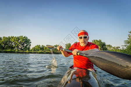 高级男护甲员在赛艇上受训在湖挂有翼桨运动模糊的背景图片