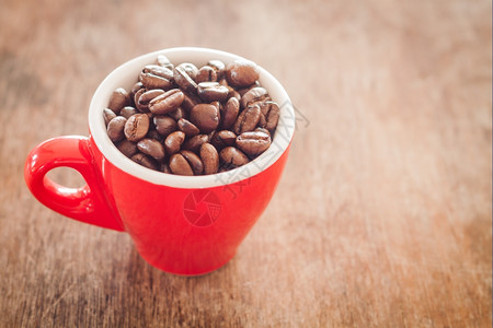 红咖啡杯和木制桌上的咖啡豆股票照片背景图片