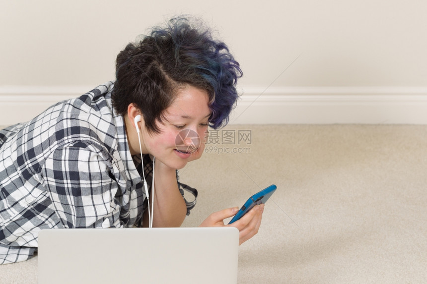 微笑的少女看着手机电脑放在前台躺家里听音乐