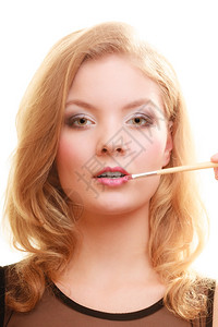 化妆师将口红和配饰工具用在女嘴唇上图片