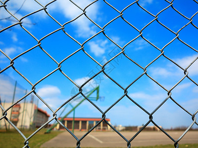 模糊篮球场背景的金属网状铁丝栅栏背景图片