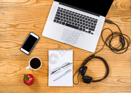 工作桌面由膝上型计算机耳笔记本咖啡手机和苹果组成图片