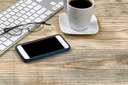 近距离的手机阅读眼镜键盘和黑咖啡在生锈的桌面上图片