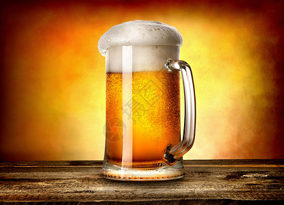 木桌和黄色背景的杯子啤酒图片