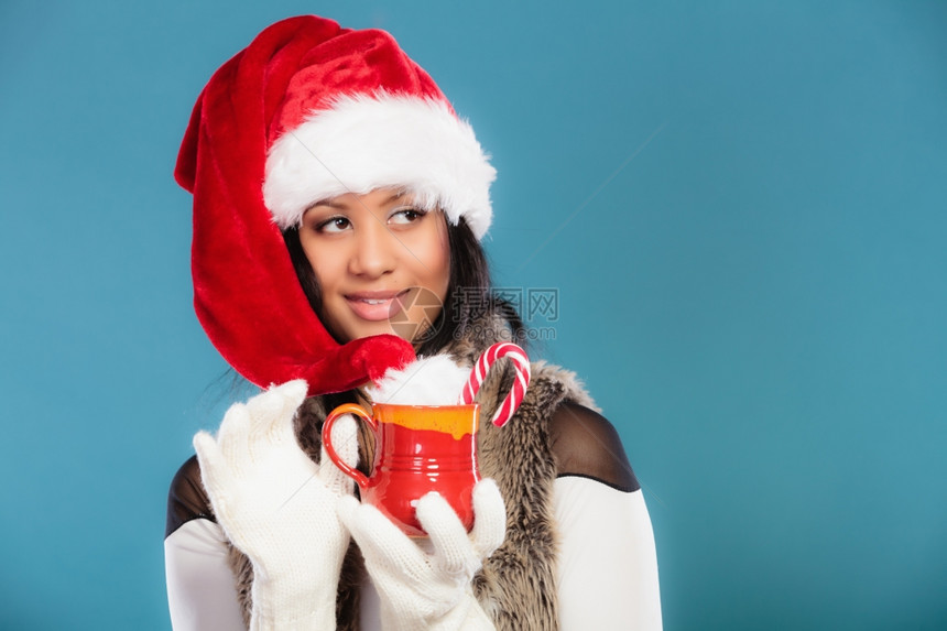 混合种族少女身着圣塔帮手帽子拿着红杯喝热饮料图片