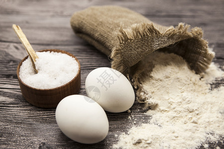 自制盲袋素材小麦面粉装在画布袋里一个大块的盐汁木头生鸡蛋准备在美丽的黑木头背景上做自制面包团背景