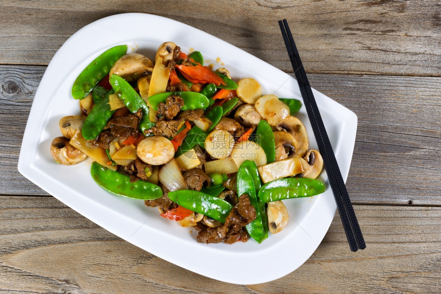 亚洲菜的高度角观包括切片多汁牛肉大米洋葱蘑菇青豆和红胡椒图片