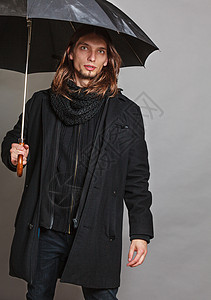 黑色雨伞穿着黑色大衣的英俊时尚男子肖像和拿着雨伞的围巾背景