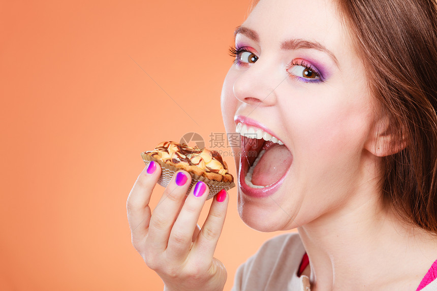 女人张开嘴手拿着蛋糕橙色背景的蛋糕图片