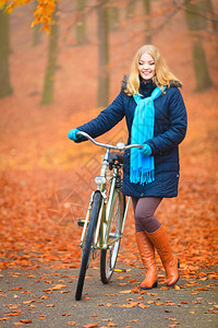 穿着围巾的年轻女孩骑着自行车在公园停顿图片