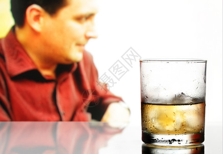 威士忌杯子冰和男在背景中分心男在背景中图片