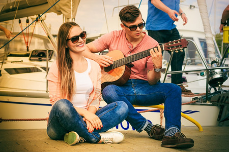 坐在船上弹琵琶的女孩快乐的情侣在户外弹吉他背景