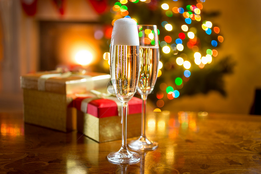 餐桌上两杯香槟对抗圣诞节装饰的壁炉图片
