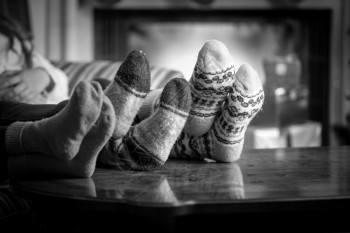 穿着羊毛袜子的黑白相近身家庭在壁炉升温图片