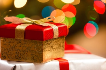 红色圣诞盒带有彩色灯光背景的金丝带图片