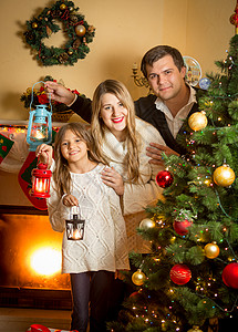 圣诞灯笼素材圣诞树上装着灯笼的幸福家庭肖像背景