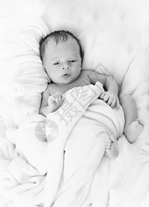 黑白照片可爱男孩的照片被毯子覆盖在床上的可爱男孩婴儿室高清图片素材