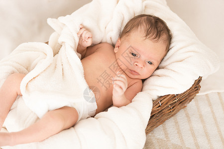 美丽的新生婴儿躺在毯子下的大篮里软的高清图片素材