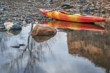 河流多彩的皮艇在岩石海岸上划桨树反射娱乐概念图片