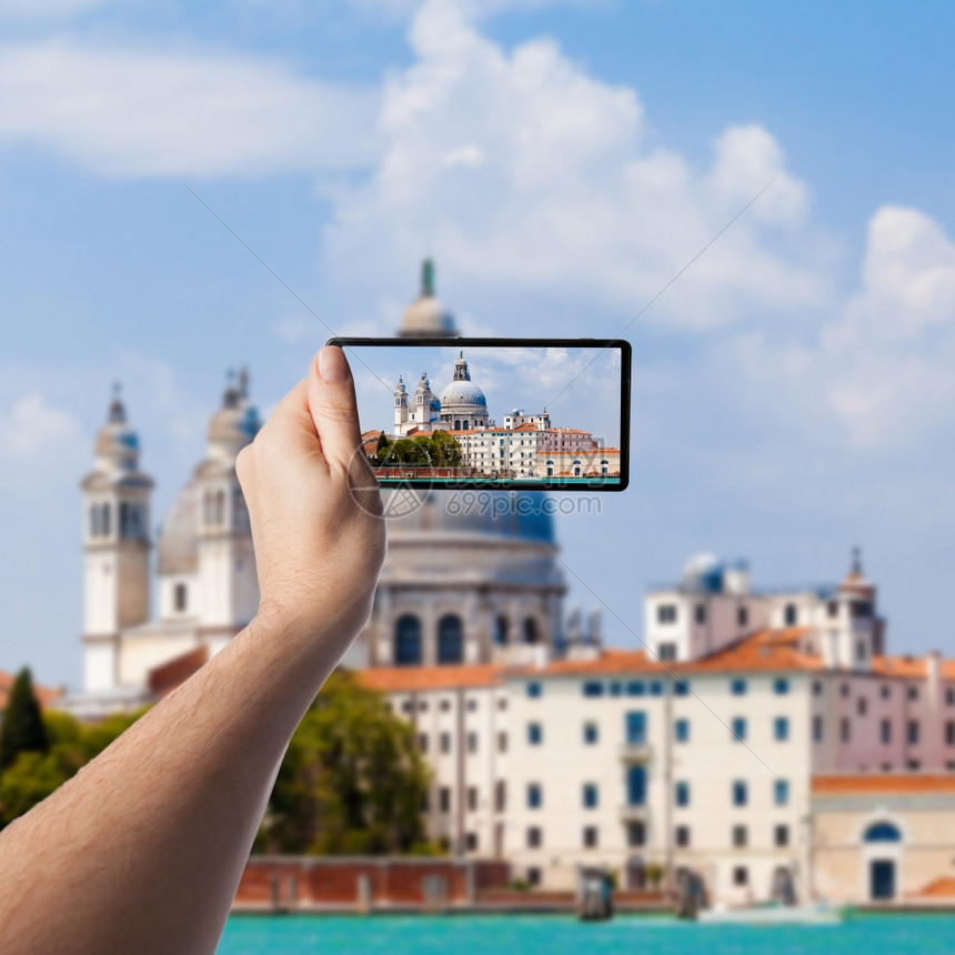 意大利威尼斯运河和巴西利卡圣玛丽亚德拉萨鲁特在智能手机上拍照图片