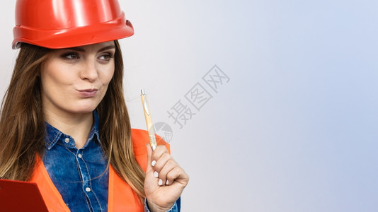 女建筑工人结构程师穿橙色背心红硬头盔的建筑工结构程师持有笔文件垫工业作安全室中帽子高清图片素材