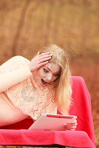 秋天公园的年轻女使用电脑平板浏览互联网图片